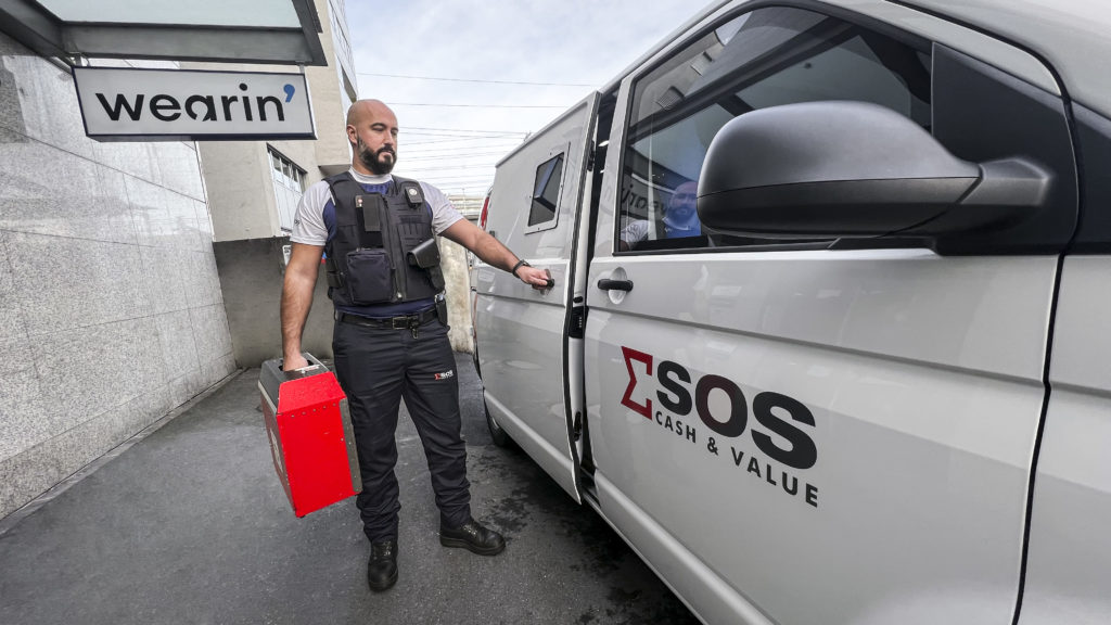 Photograph of a SOS Cash & Value agent wearing a Wearin' integrated vest transporting a payload into his vehicle