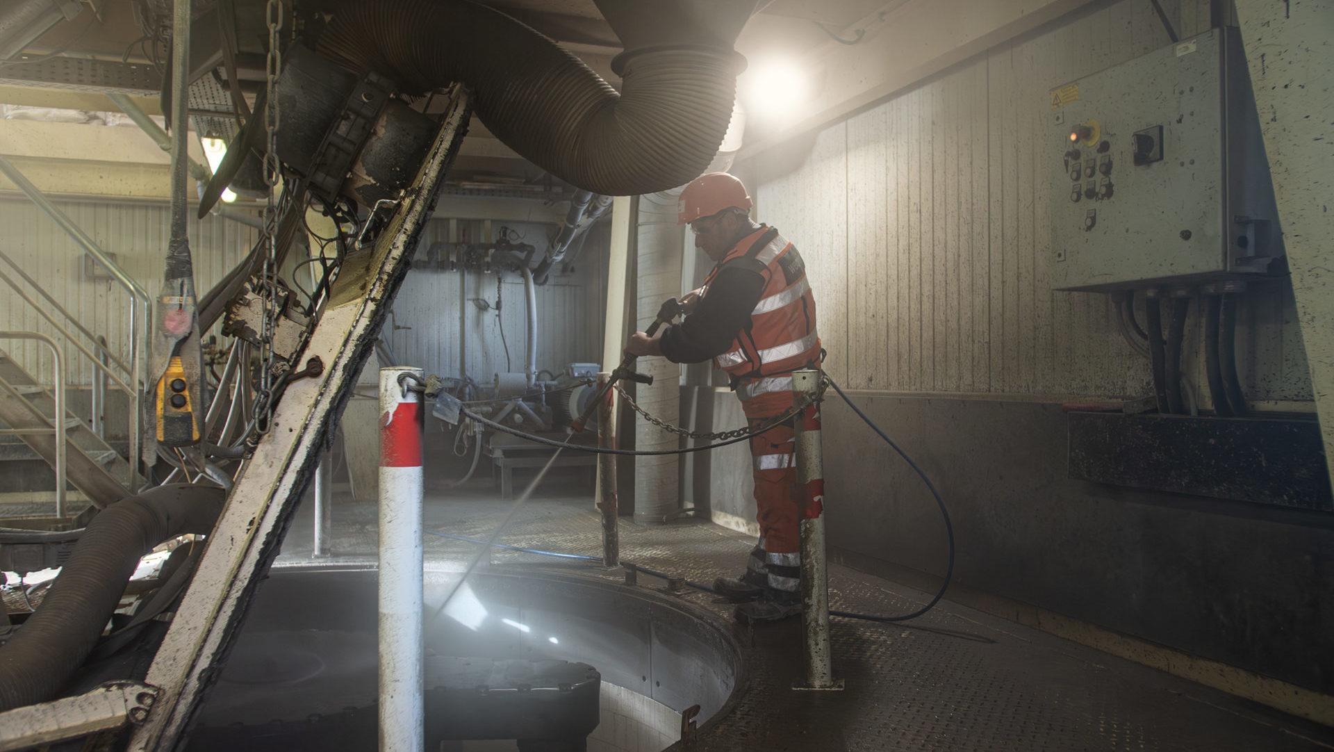 Industrial lone worker wearing protective gear operating heavy equipment in a confined facility