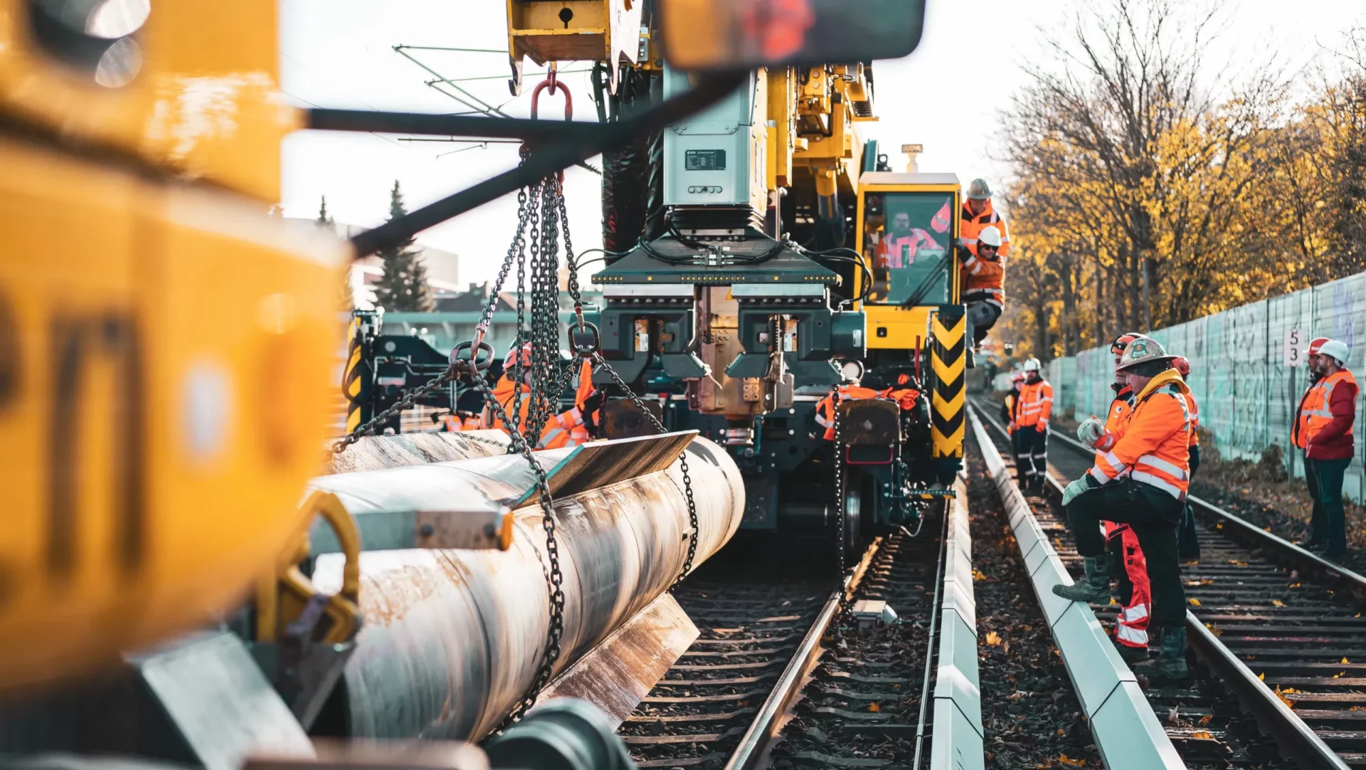 Railway maintenance workers operating heavy machinery on active tracks